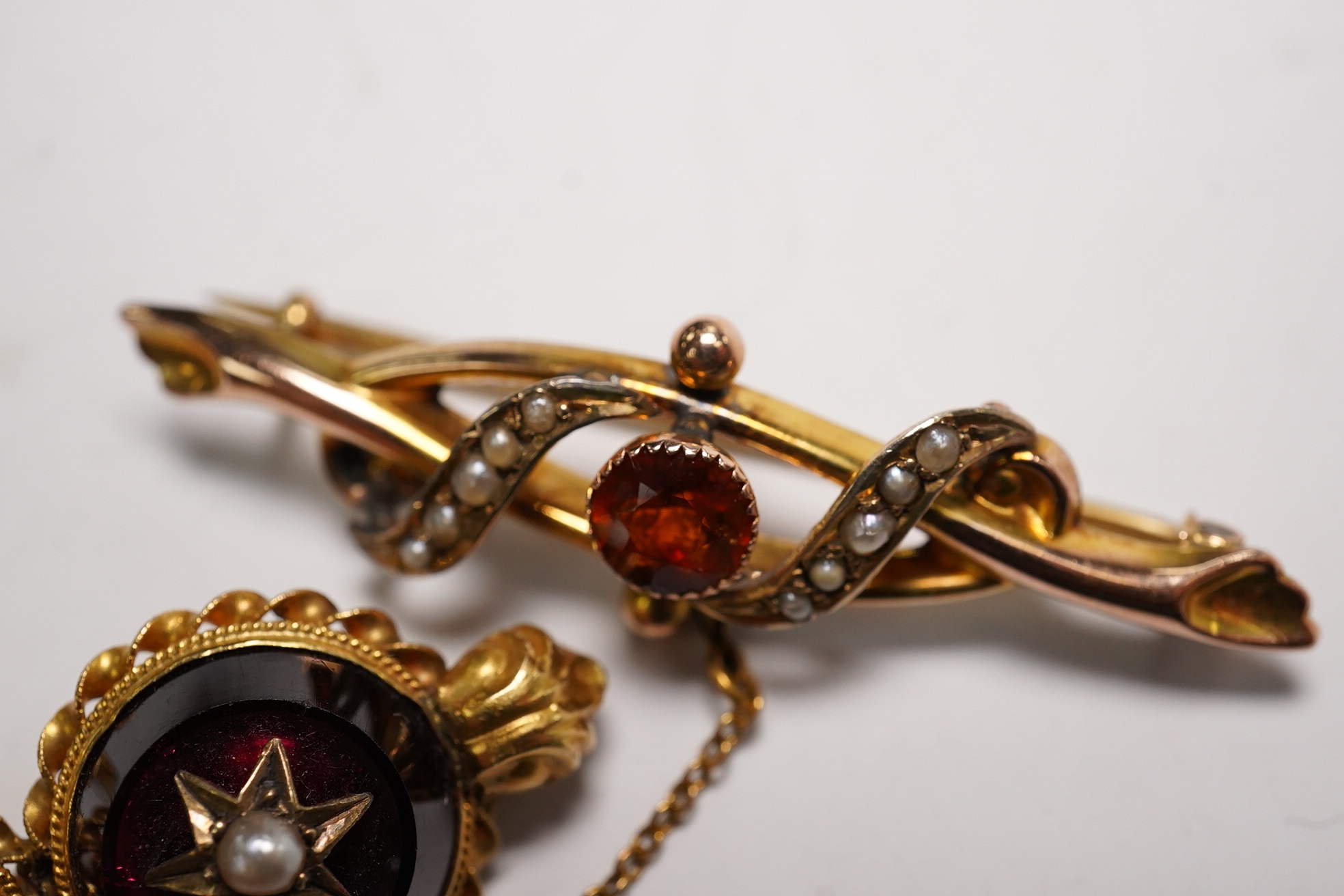 An Edwardian 9ct gold, hessonite garnet and seed pearl cluster set bar brooch, 42mm and a Victorian yellow metal, garnet and seed pearl set bar brooch, gross weight 7.3 grams, Condition - fair to good
